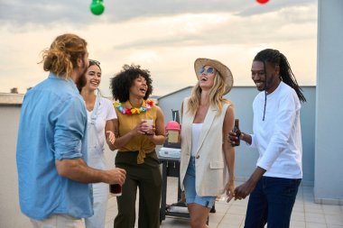 Bir yaz akşamı çatıda kutlama yaparken çeşitli arkadaşlar kahkahalarla gülüyor ve içkinin tadını çıkarıyorlar.