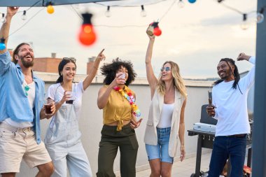 Beş tane çok ırklı arkadaş çatıda neşeyle dans ediyor, bir yaz akşamında parlayan sicim ışıkları altında içki içip kahkaha atıyorlar.