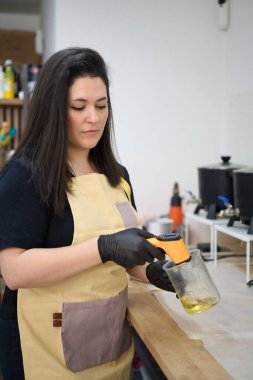 Yetenekli zanaatkar, atölyesinde mum yapımında ideal koşulları sağlamak için kızılötesi termometre kullanarak erimiş balmumunun sıcaklığını kontrol eder.