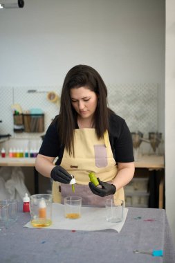 Yoğunlaştırılmış sanatkar erimiş balmumuna yeşil boya ekliyor, canlı bir stüdyoda el yapımı mumlar yapıyor.