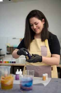 Dişi zanaatkar dikkatlice eritilmiş balmumuna boya ekliyor. Canlı el yapımı atölyesinde eşsiz ve renkli mumlar yaratıyor.