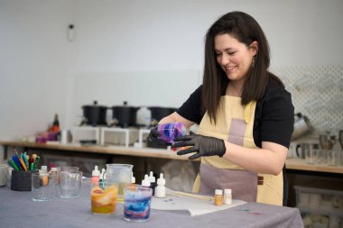 Eldiven ve önlük takan gülümseyen usta atölyesinde renkli balmumu ve aletlerle el yapımı mumları dikkatlice hazırlıyordu.