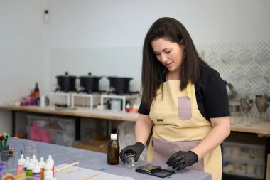 Mumcu, canlı ve organize bir atölyede ev yapımı mumlar yapmak için malzemeler hazırlıyor.