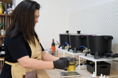 Yetenekli bir zanaatkar, parlak stüdyosunda el yapımı mumlar yapmaya hazırlanırken bir dereceye kadar balmumu ölçer.