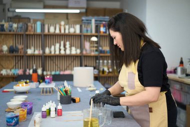 Kadın sanatçı, cam kavanoza eritilmiş balmumu dökerek canlı stüdyosunda el yapımı mumlar yakıyor.