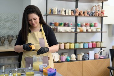 Mumcu, yaratıcı küçük renkli atölyesinde el yapımı mumlar yapmak için termometre ölçüm sıcaklığı kullanıyor.