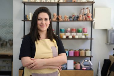 Renkli atölyesinde gururla duran bir kadın mum imalatçısı portresi, el yapımı mumlar ve el sanatlarıyla çevrili, tutkusunu ve uzmanlığını sergiliyor.