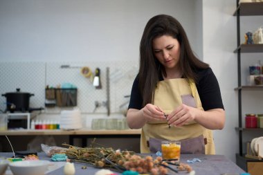 Renkli atölyede el yapımı mumlara dekoratif kurutulmuş çiçekler eklemek, eşsiz ve kişiselleştirilmiş hediyeler yaratmak.