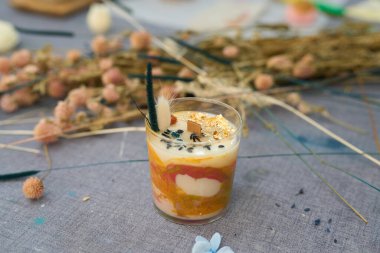 Kurumuş çiçekler, altın yapraklar ve diğer süslemelerle süslenmiş renkli el yapımı mum, mum yapımının yaratıcılığını gözler önüne seriyor.