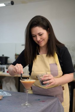 Kadın mum imalatçısı atölyesindeki cam şeklindeki mumun son rötuşlarını yapıyor.