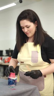 Sanatçı kadın cam kavanoza renkli balmumu karıştırıyor. Parlak atölyesinde eşsiz el yapımı mumlar yapıyor.