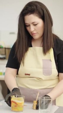 Zanaatkar, atölyesinde el yapımı mum yaparken katmanlı cama dikkatlice altın boya ekler.