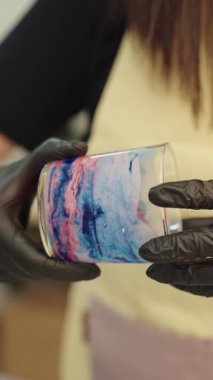 Camda el yapımı renkli mum sunan siyah koruyucu eldivenler giyen profesyonel bir zanaatkar, yaratıcı küçük işletme üretim sürecini ön plana çıkarıyor.