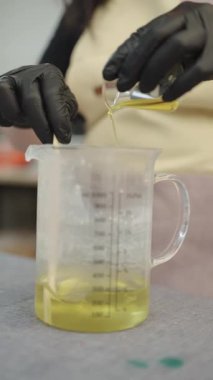 Mum imalatçısı eritilmiş balmumuna gerekli yağı ekliyor ve küçük bir atölyede el yapımı mumlar için eşsiz bir koku yaratıyor.