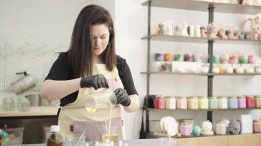 Profesyonel mumcu dikkatlice erimiş mum döker, renkli ev atölyesinde ustalıkla el işi mumlar yapar.