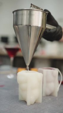 Erimiş kırmızı balmumu beyaz gövde şeklinde bir kalıba mum dökerek, mum yapımı atölyedeki metal huniyi kullanarak.