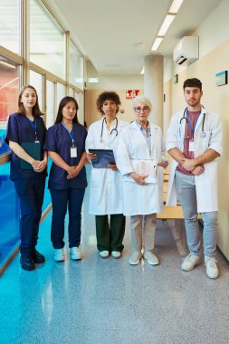 Doktorlar ve hemşireler hastane koridorunda bir arada duruyorlar, sağlık sektöründe takım çalışması ve profesyonellik gösteriyorlar.