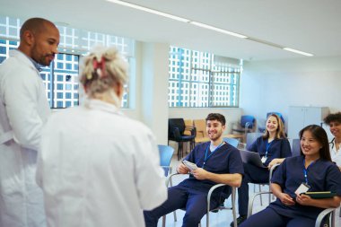 Tıbbi brifinge katılan doktorlar ve hemşireler uzmanlıklarını paylaşıyor ve modern bir hastane ortamında ideal hasta bakımı için işbirliği yapıyorlar.