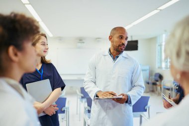 Doktorlar ve hemşireler işbirliği yapıyor, uzmanlıklarını paylaşıyor ve modern bir hastane ortamında en uygun hasta bakımını planlıyorlar.