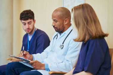 Doktor ve hemşireler hasta bilgilerini inceliyor, hastane ortamında ekip çalışması ve sağlık hizmetleri işbirliğini vurguluyor