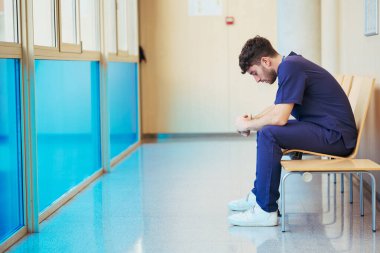 Bitkin bir doktorun hastane koridorunda mola vermesi tıp mesleğinin gerekliliğini ve hasta bakımını yansıtıyor.