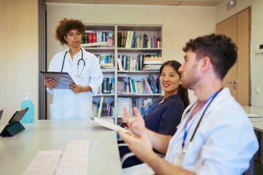 Doktorlar ve hemşireler işbirliği yapıyor, tıbbi kayıtları ve röntgenleri analiz ediyor, sağlık hizmetlerinde takım çalışması gösteriyor