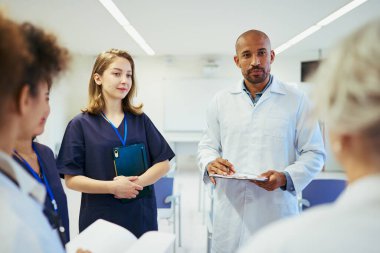 Doktorlar ve hemşireler iş birliği yapıyor, uzmanlıklarını paylaşıyor ve modern bir hastane ortamında en uygun hasta bakımını planlıyorlar.