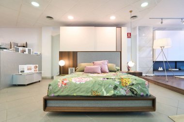 Mobilya sergisinde çiçeklerle döşenmiş modern yatak odası mobilyaları ve şık lambalar.