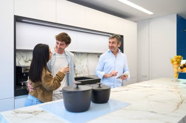 Çağdaş bir mobilya galerisinde modern mutfak tasarımı fikirlerini tartışan genç bir çift bir iç tasarımcıyla takılıyor.