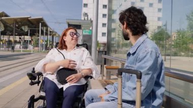 Tramvay durağında turistle dostça sohbet eden neşeli kadın, şehir bağlantısını ve ulaşılabilirliği gösteriyor