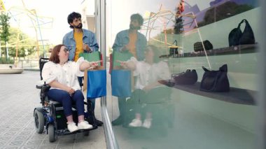 Kentsel alışveriş deneyiminden hoşlanan bir grup arkadaş, elektrikli sandalye gözleme mağazası penceresi kullanan bir kadın, modern şehir ortamında ulaşılabilirlik ve beraberlik sergiliyor
