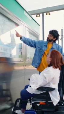 Toplu taşıma durağında yol tarifi vererek tekerlekli sandalyedeki kadına yardım eden yardımsever bir adam.