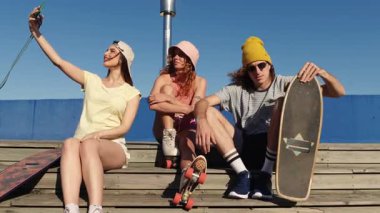 Genç arkadaşlar, güneşli yaz günlerinde manzaralı okyanus manzarasına bakan ahşap merdivenlerde selfie çekerken yoldaşlık anını yakalıyorlar.