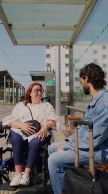 Sevgili çift, gerçek anı paylaşıyor, tekerlekli sandalye kullanıcısı ve partneri şehir ulaşım platformunda güneşli yaz gününde sıcacık bir şekilde bağlanıyor.