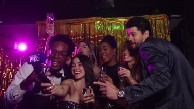 Neşeli arkadaşlar selfie çekiyor, şampanya bardakları tutuyor, yeni yıl arifesini canlı bir partide kutluyorlar.