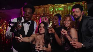 Bir grup zarif arkadaş yeni yıl partisinde şampanya kadehleri ve şenlikli altın arkaplanlı selfie çekiyorlar.