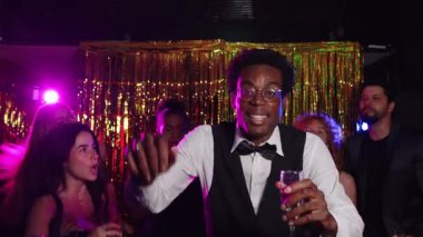 Neşeli arkadaşlar dans ediyor ve şampanya içiyor, yeni yıl arifesini bir gece kulübünde kutluyorlar, ağır çekimde.