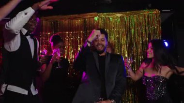 Arkadaşlar yeni yılın tadını çıkarıyorlar. Dans ve içki, canlı bir yavaş çekim montajı.