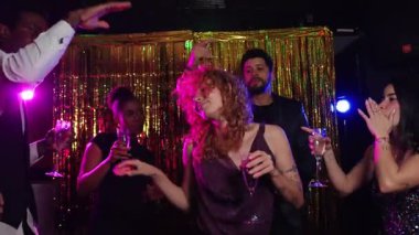 Arkadaşlar şenlik gecesinin tadını çıkarıyorlar, yeni yıl arifesini köpüklü şarapla kutluyorlar, altın zemine karşı enerjik bir şekilde dans ediyorlar, keyifli anı şık yavaş çekimde paylaşıyorlar.