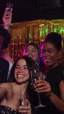 Gençler yeni yıl arifesinde bir gece kulübünde şenlikli bir atmosferde şampanya kadehleri kaldırırken yavaş çekimde yakalandılar.