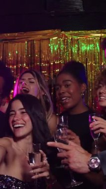 Mutlu çoklu etnik arkadaşlar yeni yıl partisinde selfie çekiyor, gülüyor ve kadeh kaldırıyor.