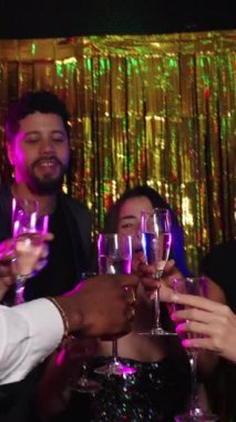 Mutlu arkadaşlar yeni yıl arifesini kutluyor, altın bir arka plan önünde şampanya kadehleriyle kadeh kaldırıyorlar.