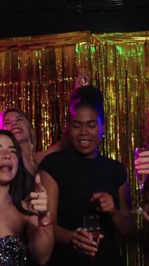 Neşeli arkadaşlar şampanya kadehlerini kaldırıyor, yeni yıl arifesini kutluyorlar, neşeli bir atmosferde, ağır çekimde.