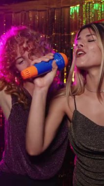 Karaokeyi seven iki genç kadın enerjik ve tutkulu bir atmosferde şarkı söylüyorlar.