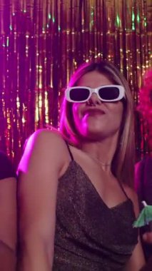 Genç bir kadının dans ettiği ve gece kulübünde eğlendiği canlı pembe ve altın ışıklı bir video.