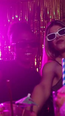 Genç insanlar kameraya yavaş çekimde kokteyl sunuyor, disko partisinde gece hayatının tadını çıkarıyorlar.