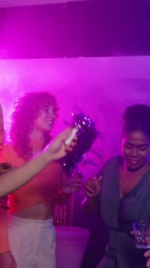 Genç yetişkinler gece kulübü partisinde dans edip içiyorlar. Gece hayatı ve müzikten zevk alıyorlar. Yavaş çekim.