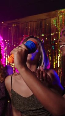 Arkadaşlar karaoke gecesinde coşkuyla şarkı söylüyor, tutkulu performanslarını canlı bir enerji ve neşeli bir gece kulübü ortamında paylaşıyorlar.