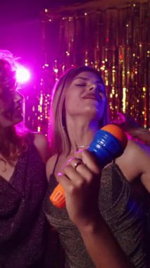 Karaokeden hoşlanan kadınlar, ağır çekimde mikrofonla şarkı söylemek, canlı bir gecede eğlenmek.