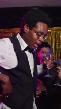 Yavaş çekim, arkadaşlarıyla dans eden şık bir adamı yakalar. İçkinin ve partinin coşkulu atmosferinin tadını çıkarır.